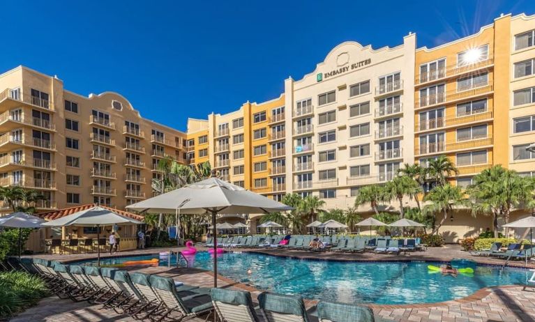 Stunning outdoor pool with loungers and umbrellas at Embassy Suites By Hilton Deerfield Beach Resort & Spa.