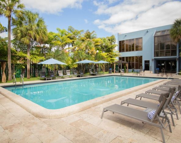 Outdoor pool with pool loungers at Regency Miami Airport By Sonesta.