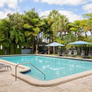 Outdoor pool with trees at Regency Miami Airport By Sonesta.