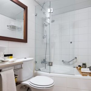 Guest bathroom with shower and bath at Prima Royale Hotel.