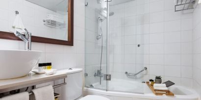 Guest bathroom with shower and bath at Prima Royale Hotel.