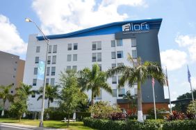 Hotel exterior with palm trees at Aloft Miami Doral.
