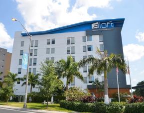 Hotel exterior with palm trees at Aloft Miami Doral.
