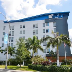 Hotel exterior with palm trees at Aloft Miami Doral.
