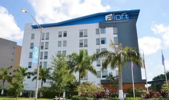 Hotel exterior with palm trees at Aloft Miami Doral.
