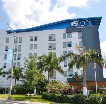 Hotel exterior with palm trees at Aloft Miami Doral.
