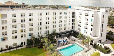 Hotel pool and hotel exterior at Aloft Miami Doral.
