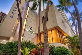 Hotel exterior with palm trees at Hyatt Place Waikiki Beach.