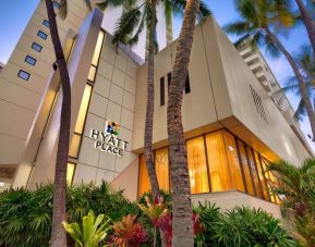 Hotel exterior with palm trees at Hyatt Place Waikiki Beach.