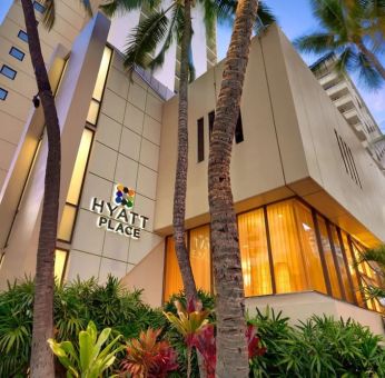 Hotel exterior with palm trees at Hyatt Place Waikiki Beach.