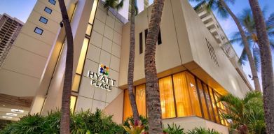 Hotel exterior with palm trees at Hyatt Place Waikiki Beach.