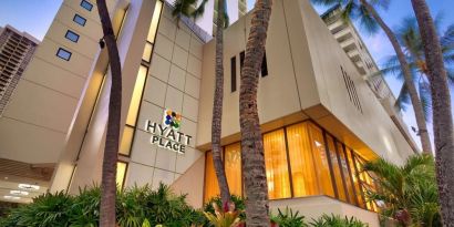 Hotel exterior with palm trees at Hyatt Place Waikiki Beach.