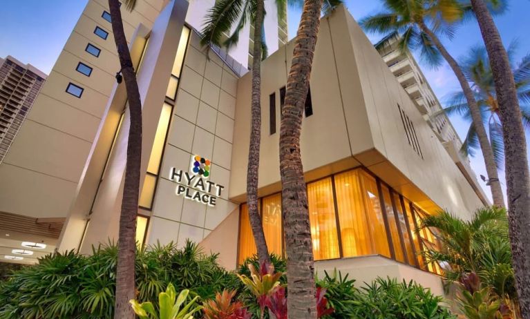 Hotel exterior with palm trees at Hyatt Place Waikiki Beach.