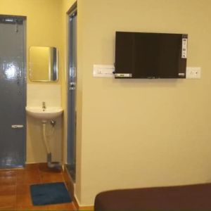 Day room with TV and private bathroom at The Nisarga Residency.