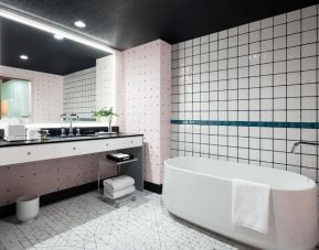 Spacious bathroom with bath and shower at Graduate By Hilton New York.