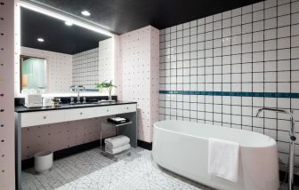 Spacious bathroom with bath and shower at Graduate By Hilton New York.