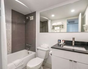 Guest bathroom with shower and bath at Ramada Plaza Marco Polo Beach Resort.