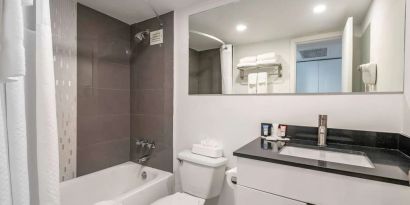 Guest bathroom with shower and bath at Ramada Plaza Marco Polo Beach Resort.