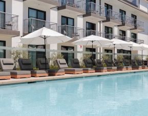 Outdoor pool with loungers and umbrellas at Lum Hotel Inglewood.