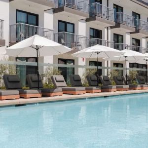 Outdoor pool with loungers and umbrellas at Lum Hotel Inglewood.