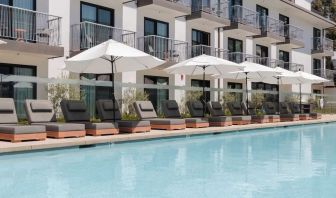 Outdoor pool with loungers and umbrellas at Lum Hotel Inglewood.