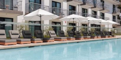 Outdoor pool with loungers and umbrellas at Lum Hotel Inglewood.