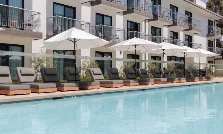 Outdoor pool with loungers and umbrellas at Lum Hotel Inglewood.