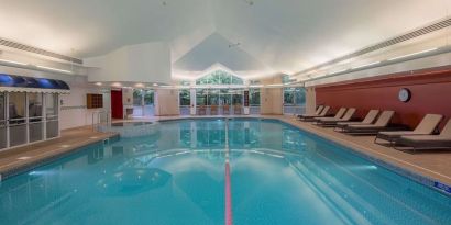 Indoor pool with lounge chairs at Hilton Leicester.