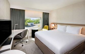 King bedroom with work desk at Hilton London Heathrow Airport.