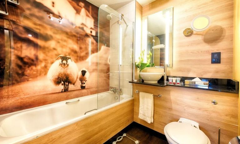 Guest bathroom with shower and tub at Leonardo Royal Hotel Edinburgh Haymarket. 