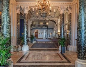 Elegant hotel lobby with marble columns and decorative chandeliers at The Grand Brighton. 