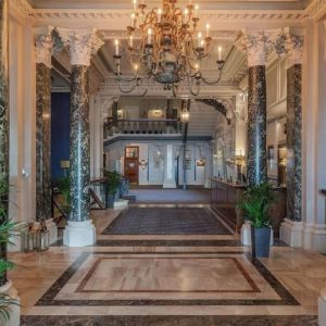 Elegant hotel lobby with marble columns and decorative chandeliers at The Grand Brighton. 