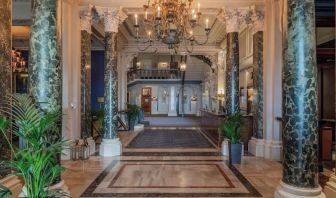 Elegant hotel lobby with marble columns and decorative chandeliers at The Grand Brighton. 