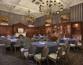 Elegant meeting room featuring round tables, chandeliers, and classic wood paneling at The Grand Brighton.