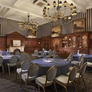 Elegant meeting room featuring round tables, chandeliers, and classic wood paneling at The Grand Brighton.