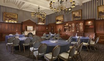 Elegant meeting room featuring round tables, chandeliers, and classic wood paneling at The Grand Brighton.