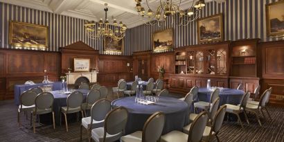 Elegant meeting room featuring round tables, chandeliers, and classic wood paneling at The Grand Brighton.