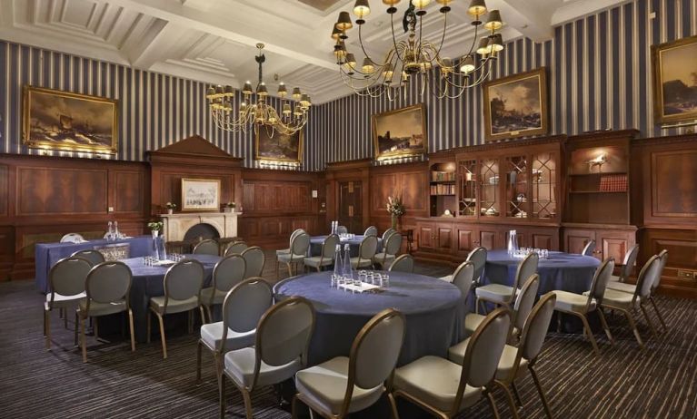 Elegant meeting room featuring round tables, chandeliers, and classic wood paneling at The Grand Brighton.