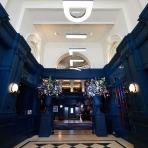 Hotel entrance with bold navy walls and modern hanging letter lights at The Dilly.  