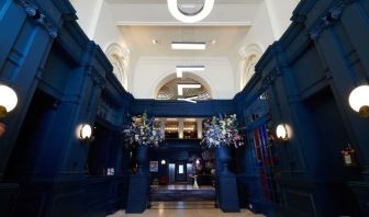 Hotel entrance with bold navy walls and modern hanging letter lights at The Dilly.  