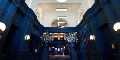 Hotel entrance with bold navy walls and modern hanging letter lights at The Dilly.  