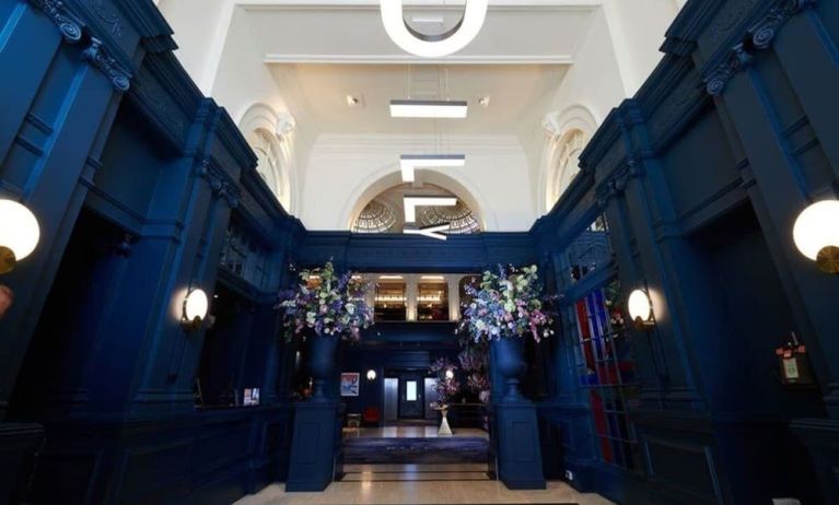 Hotel entrance with bold navy walls and modern hanging letter lights at The Dilly.  