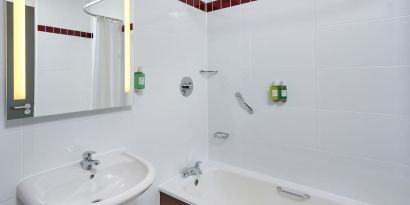 Guest bathroom with shower and tub at Leonardo Hotel Milton Keynes.