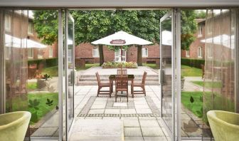 Outdoor patio with chairs, tables and sun umbrellas at the DoubleTree by Hilton Newbury North.