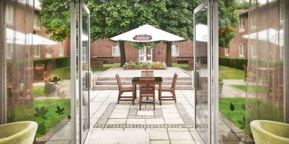 Outdoor patio with chairs, tables and sun umbrellas at the DoubleTree by Hilton Newbury North.