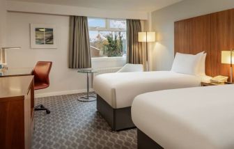 Day use room with double bed, work desk and TV at Hilton London Watford.