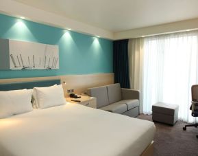 Day use room with king bed, work desk and sofa at the Hampton by Hilton London Docklands.