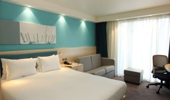 Day use room with king bed, work desk and sofa at the Hampton by Hilton London Docklands.