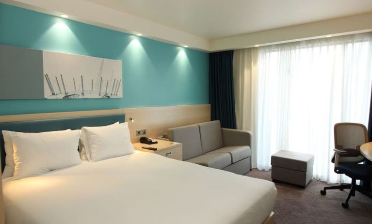 Day use room with king bed, work desk and sofa at the Hampton by Hilton London Docklands.