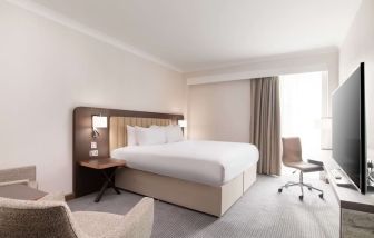 Day use room with work desk and chair, TV and sofa at the Hilton London Gatwick Airport.